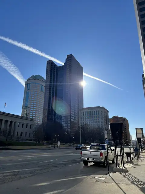 Sun-drenched skyscrapers reach for a stunning blue, contrail-filled sky.