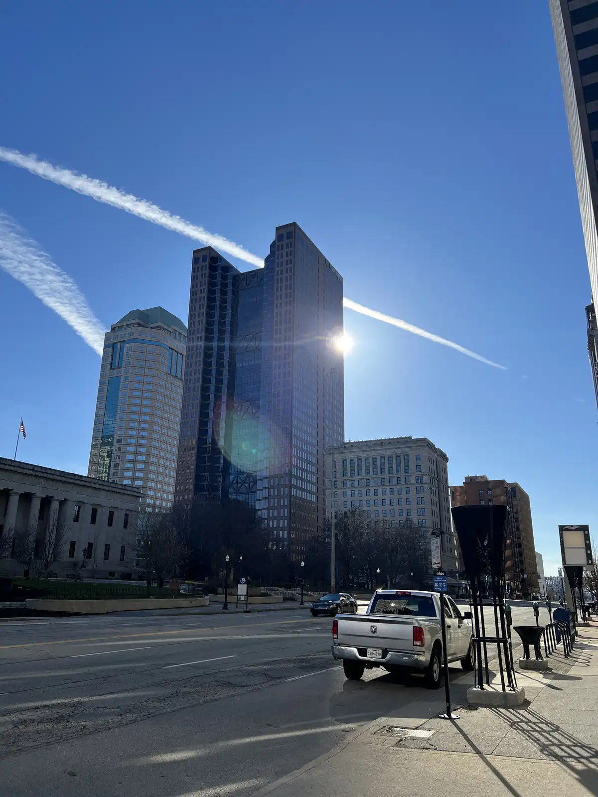 Sun-drenched skyscrapers reach for a stunning blue, contrail-filled sky. Still Frame