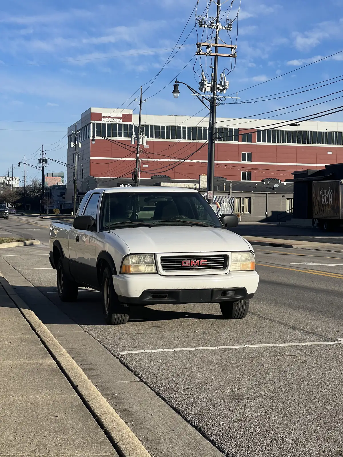 Urban everyday: A lone white pickup under a clear sky. Still Frame