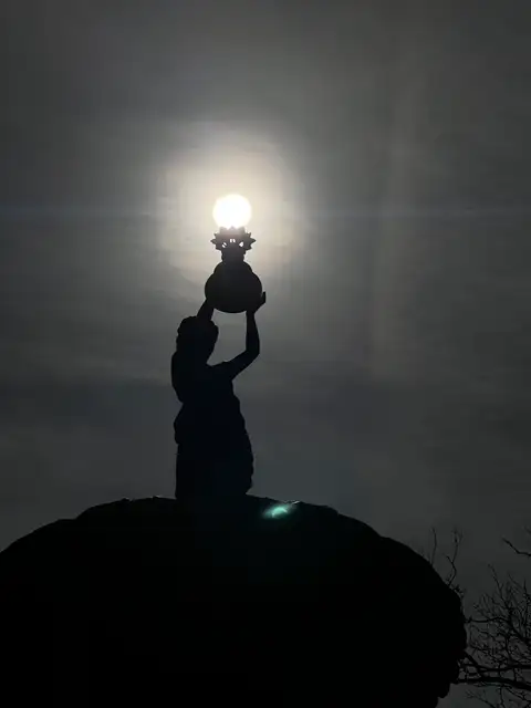 Holding the sun in her hands, a divine glow in the fading light.