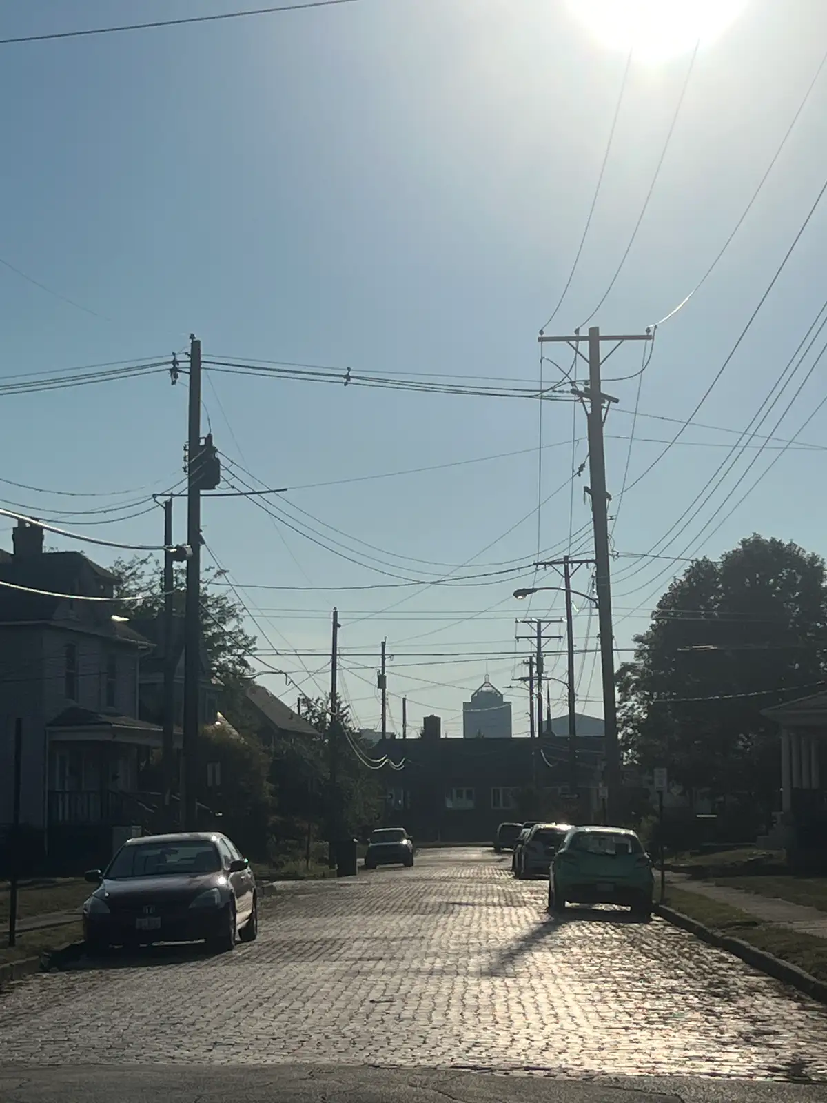 Sun-drenched cobblestones lead to distant city views. Still Frame