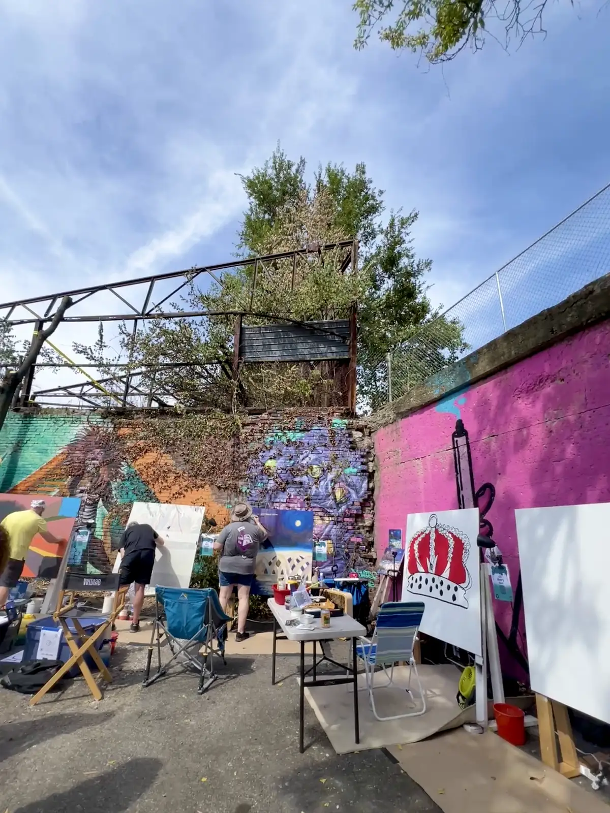 Artists bringing vibrant life and color to an outdoor mural event. Still Frame