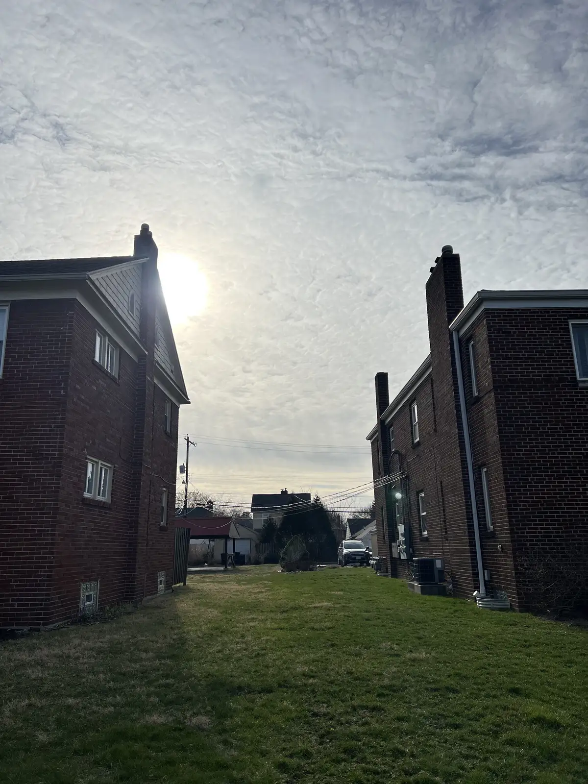 Sunlight pierces through the clouds, framed by suburban homes. Still Frame